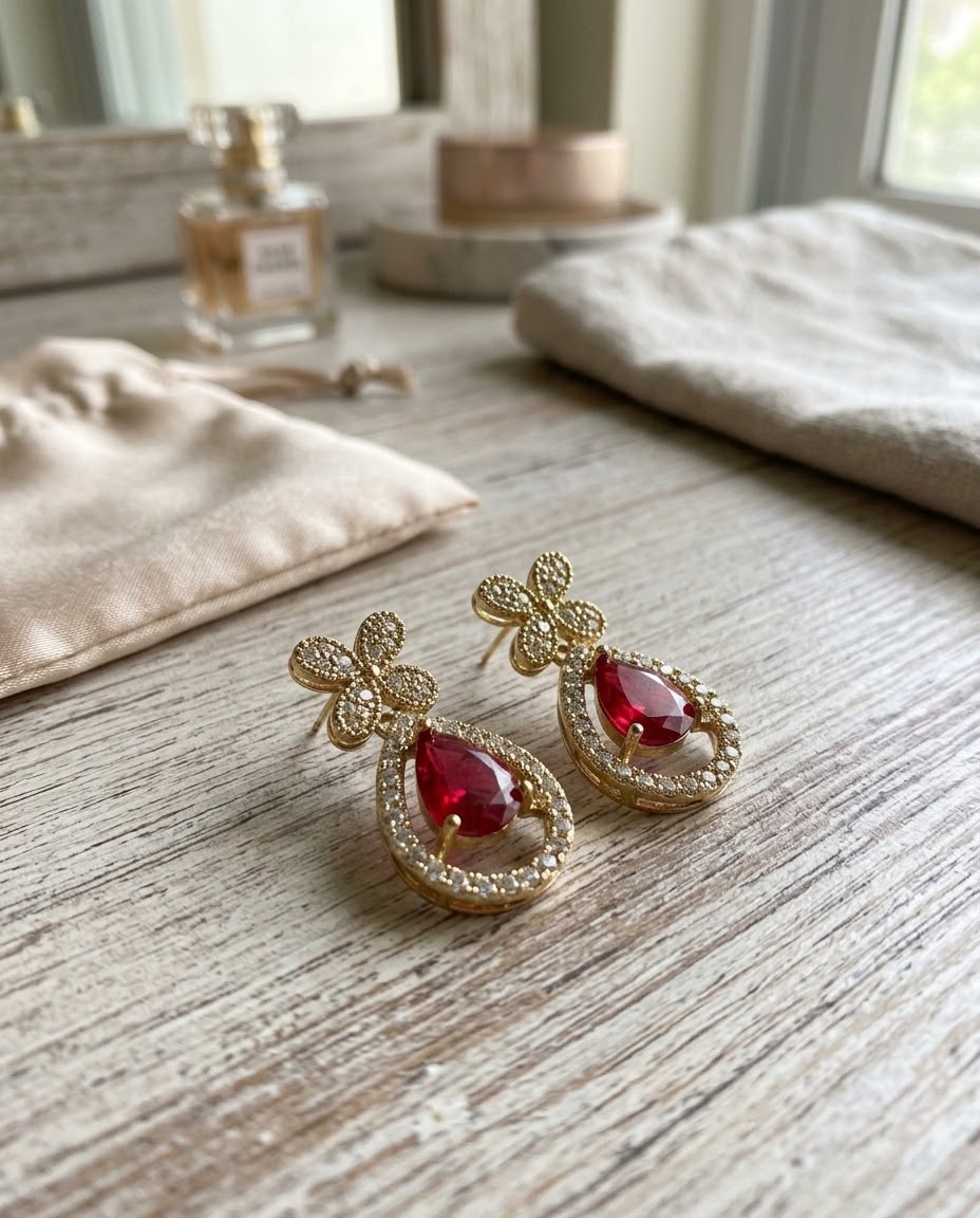 Earrings styled on a wooden table with perfume and pouches