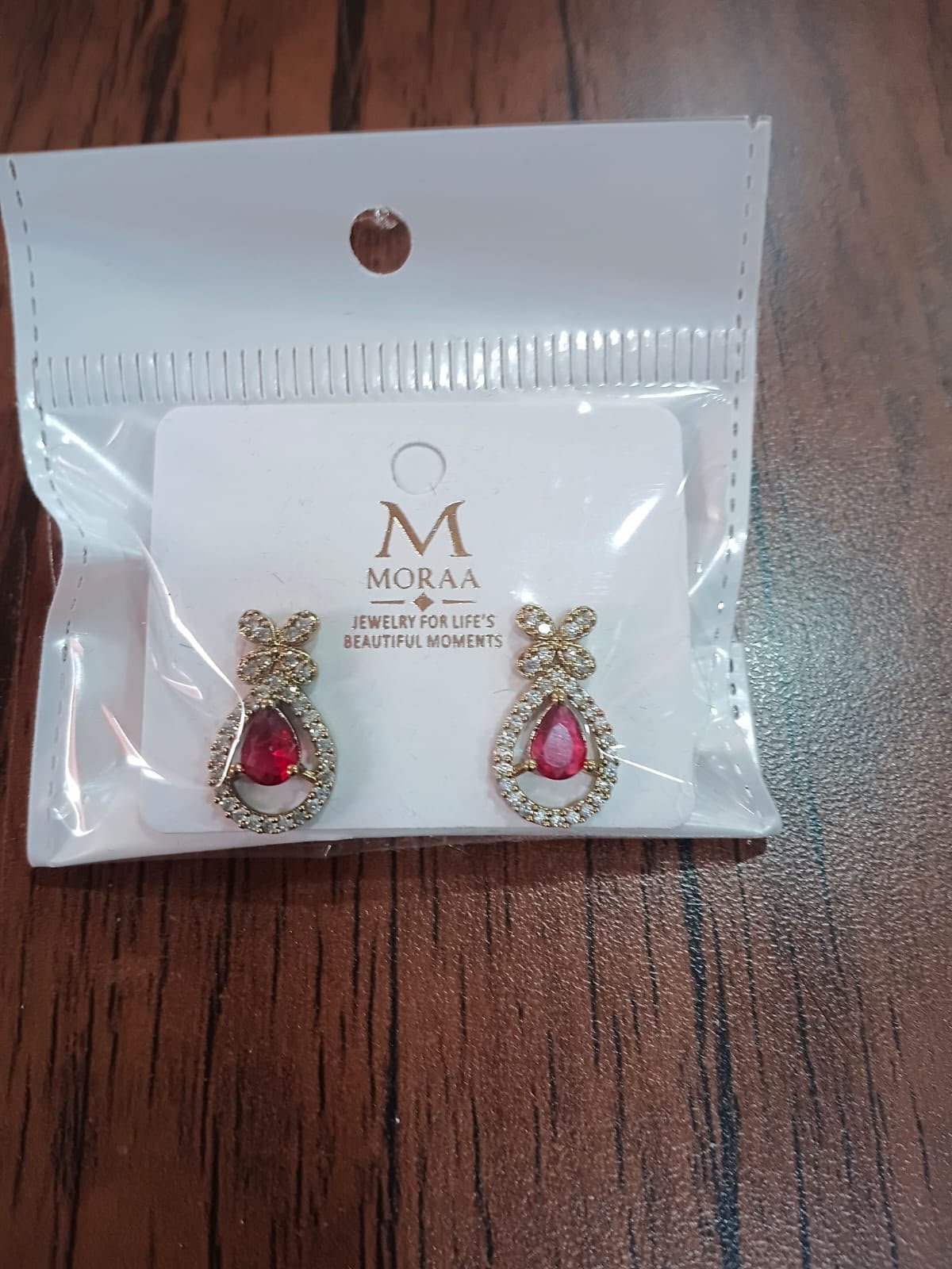 Earrings shown in their packaging on a wooden table